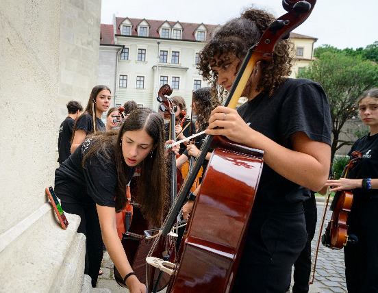 Rebecca ayuda a Luz a afinar el violonchelo, ante la atenta mirada de Noelia e Irene / Bratislava Music Agency